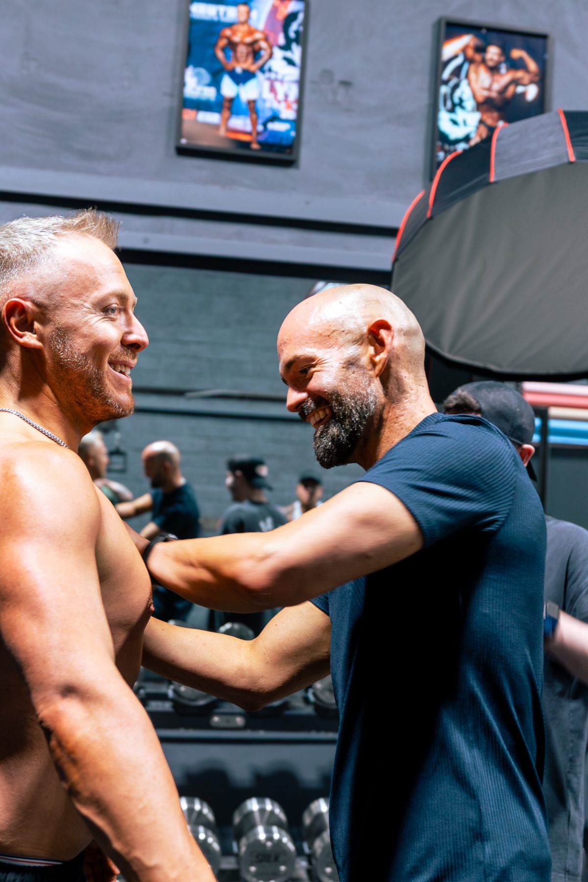 A client curling chrome dumbbells in the studio with a softbox light behind him